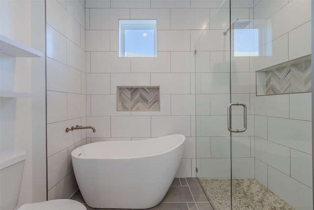 bathroom with plus walk in shower, tile patterned floors, toilet, and tile walls