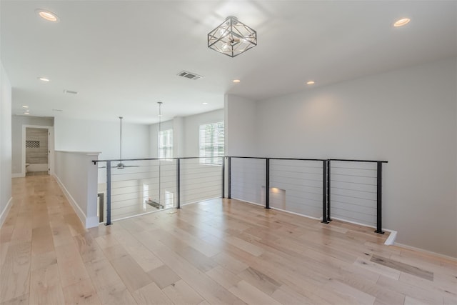 unfurnished room featuring light wood-type flooring and an inviting chandelier