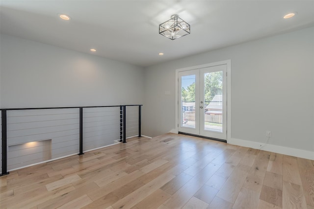 spare room with a chandelier, french doors, and light wood-type flooring