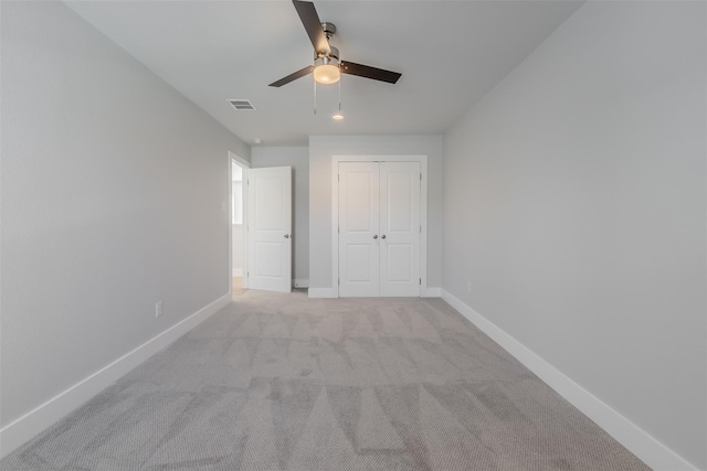 unfurnished bedroom with ceiling fan, light carpet, and a closet