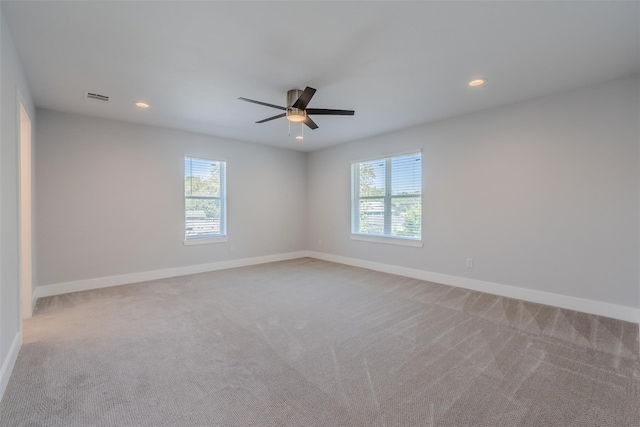 carpeted spare room with ceiling fan and plenty of natural light