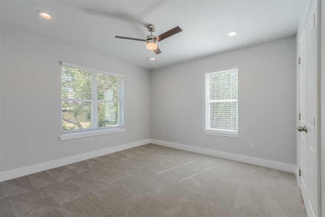 unfurnished room featuring ceiling fan, light carpet, and a wealth of natural light