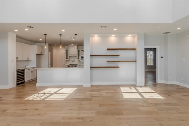 unfurnished living room featuring light hardwood / wood-style flooring and wine cooler