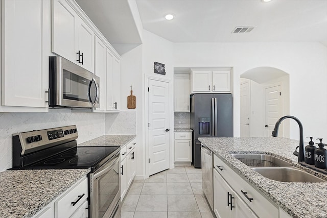 kitchen featuring white cabinetry, sink, stainless steel appliances, light stone counters, and light tile patterned floors