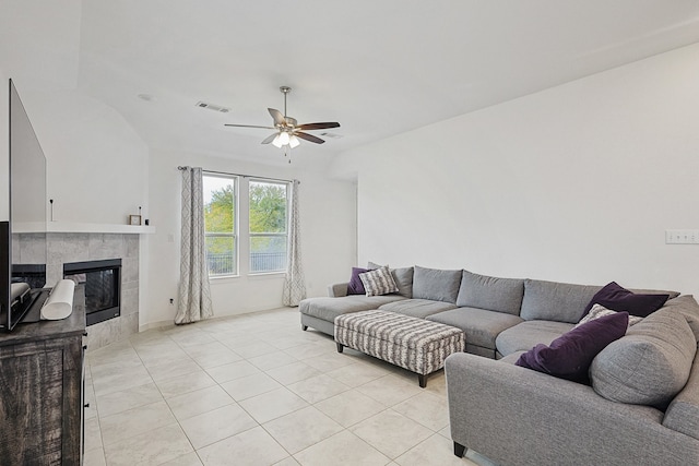 living room with a tile fireplace, light tile patterned floors, and ceiling fan