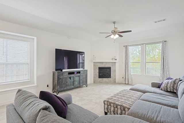 living room featuring a tile fireplace, ceiling fan, and light tile patterned floors