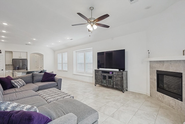 tiled living room with ceiling fan and a fireplace