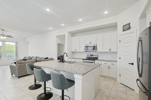 kitchen with sink, tasteful backsplash, an island with sink, white cabinets, and appliances with stainless steel finishes