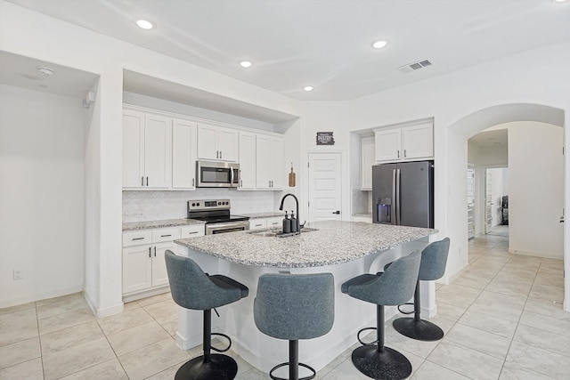 kitchen with white cabinets, appliances with stainless steel finishes, a kitchen island with sink, and sink