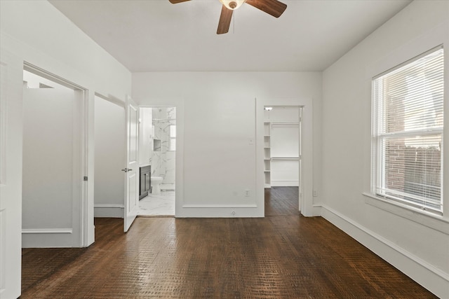 unfurnished bedroom featuring a closet, ensuite bathroom, a spacious closet, and ceiling fan