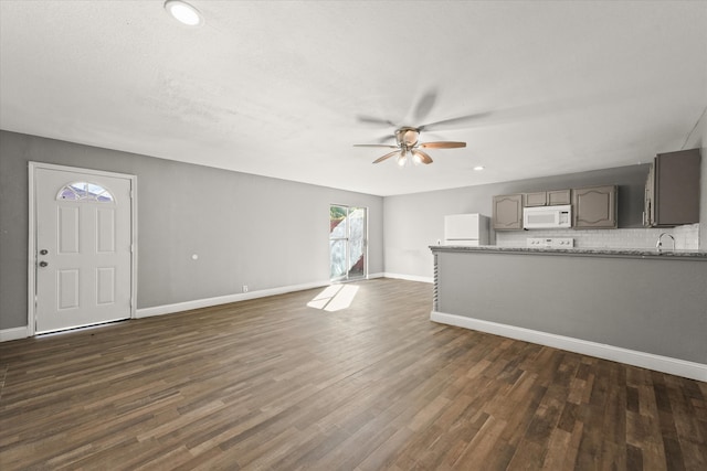 unfurnished living room featuring dark hardwood / wood-style flooring, ceiling fan, and sink