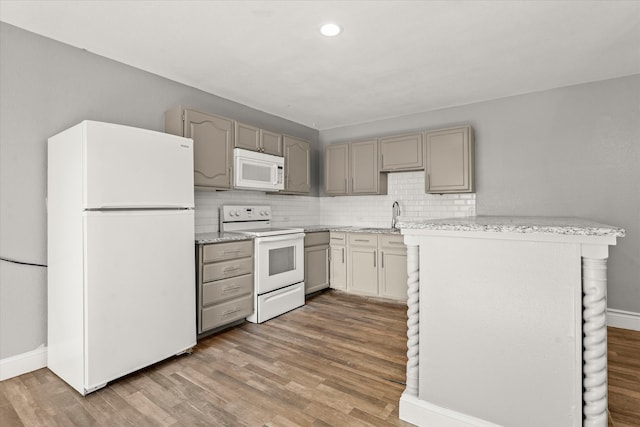 kitchen featuring backsplash, kitchen peninsula, hardwood / wood-style floors, and white appliances