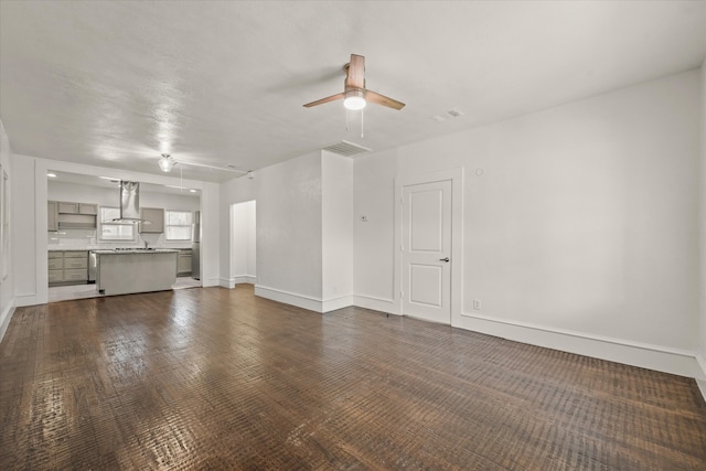 unfurnished living room featuring ceiling fan and dark wood-type flooring