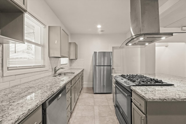 kitchen featuring island exhaust hood, decorative backsplash, light stone countertops, stainless steel appliances, and sink