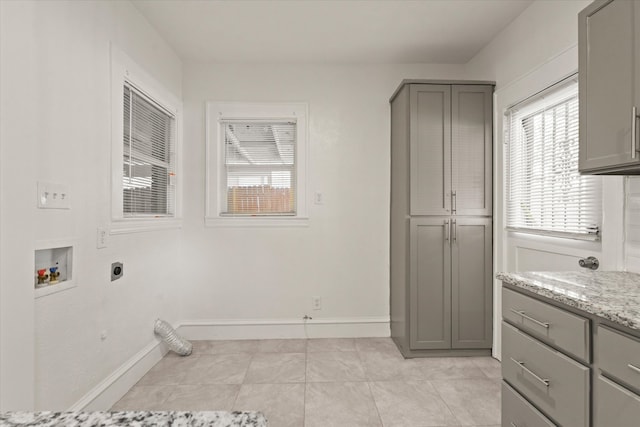 clothes washing area featuring cabinets, washer hookup, electric dryer hookup, and light tile patterned flooring