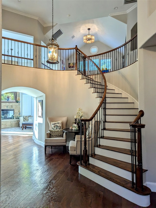 stairway featuring a fireplace, hardwood / wood-style floors, high vaulted ceiling, and crown molding