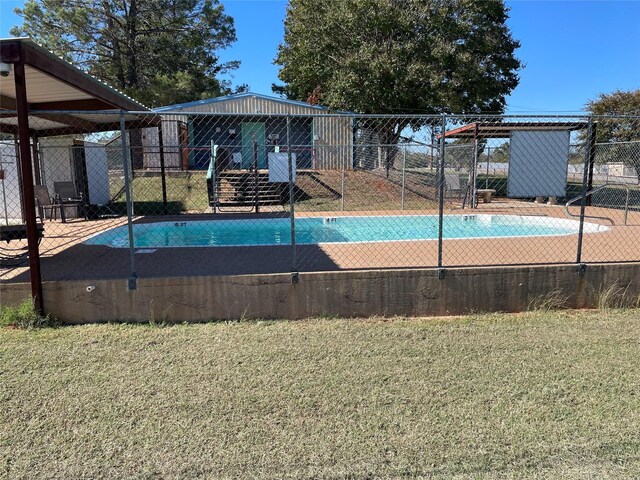 view of pool with basketball hoop and a yard