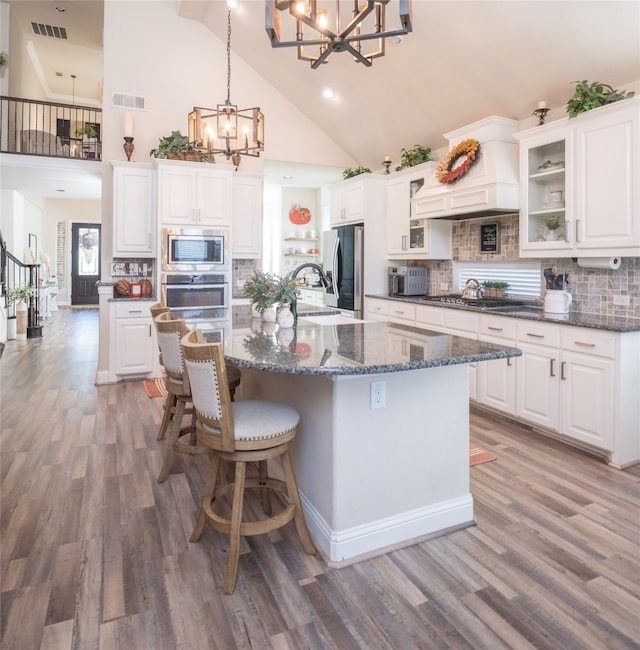 kitchen featuring tasteful backsplash, stainless steel appliances, pendant lighting, high vaulted ceiling, and white cabinets