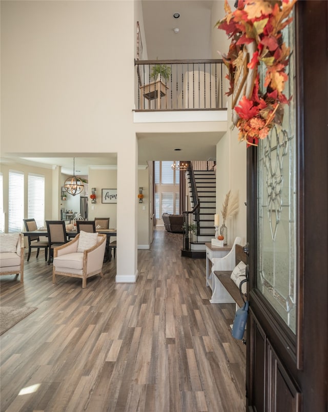 foyer with a high ceiling, hardwood / wood-style flooring, a wealth of natural light, and a notable chandelier