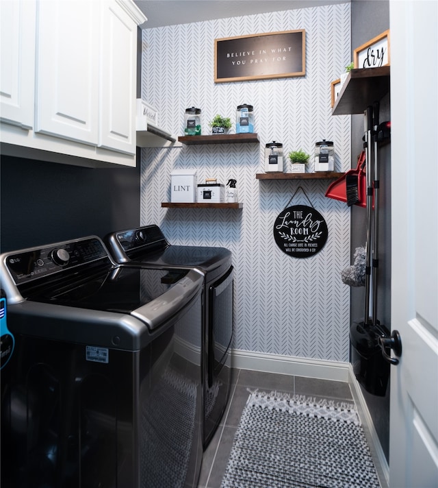 laundry area featuring washing machine and clothes dryer, dark tile patterned floors, and cabinets