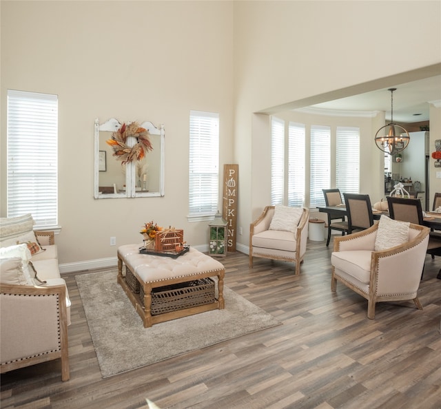 living room featuring a towering ceiling, dark hardwood / wood-style floors, and an inviting chandelier