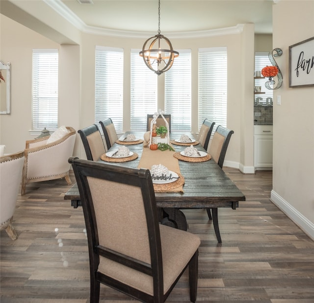 dining space with dark hardwood / wood-style floors, ornamental molding, and an inviting chandelier