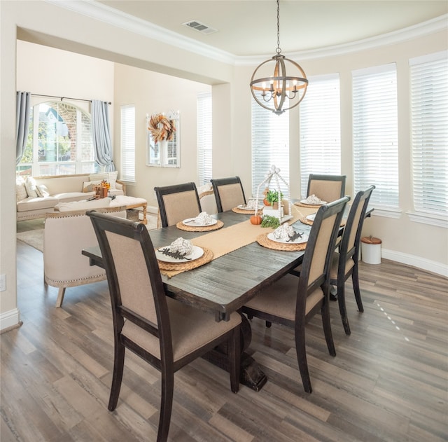 dining space with a chandelier, ornamental molding, and dark wood-type flooring