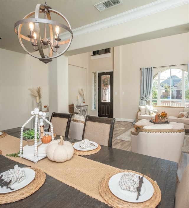 dining space with hardwood / wood-style floors, an inviting chandelier, and ornamental molding