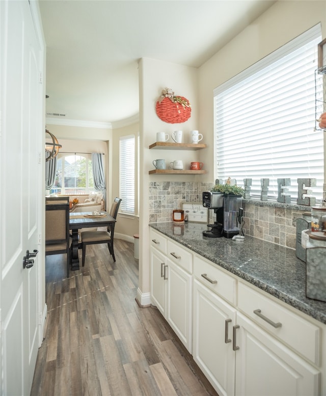 kitchen featuring decorative backsplash, white cabinetry, dark hardwood / wood-style flooring, and crown molding