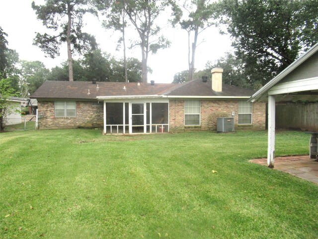 rear view of house with cooling unit, a yard, and a sunroom