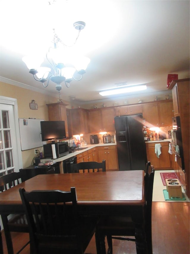 kitchen with sink, crown molding, wood-type flooring, black appliances, and a chandelier