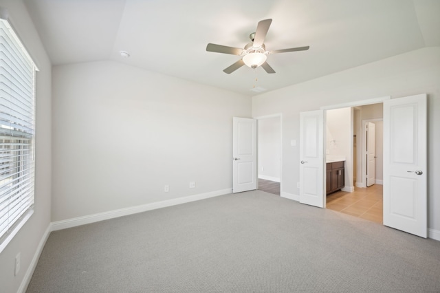 unfurnished bedroom featuring light carpet, connected bathroom, ceiling fan, and lofted ceiling