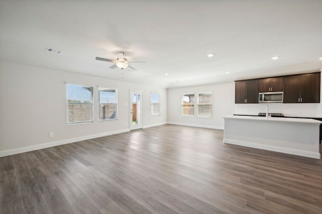 unfurnished living room featuring dark hardwood / wood-style flooring, ceiling fan, and sink