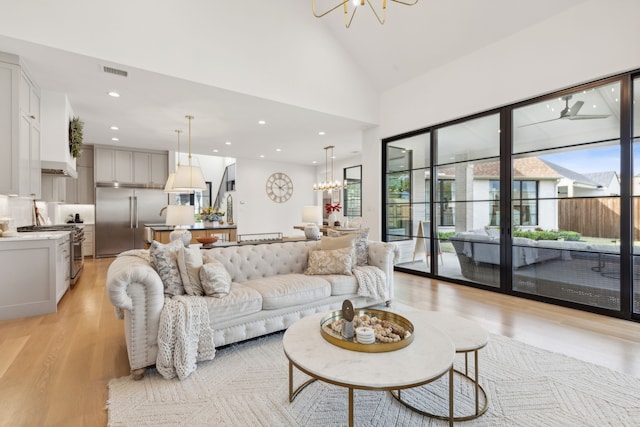 living room featuring high vaulted ceiling, light wood-type flooring, and a notable chandelier