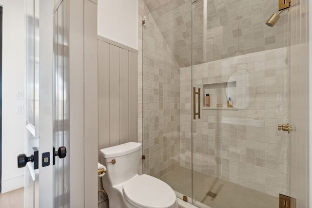 bathroom featuring toilet, a shower with shower door, and lofted ceiling