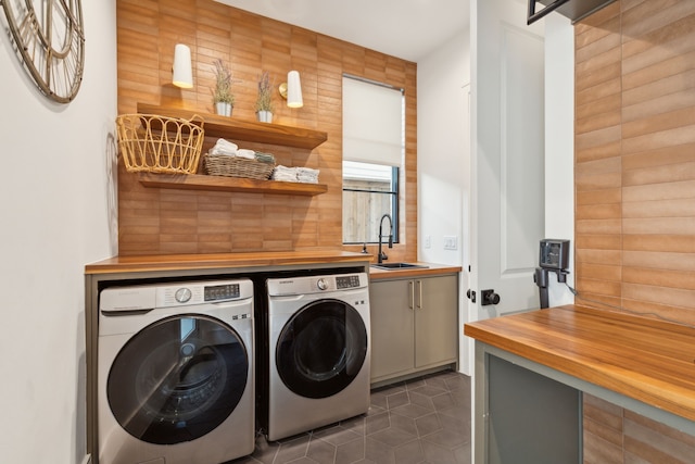 laundry room featuring cabinets, washing machine and dryer, dark tile patterned flooring, and sink