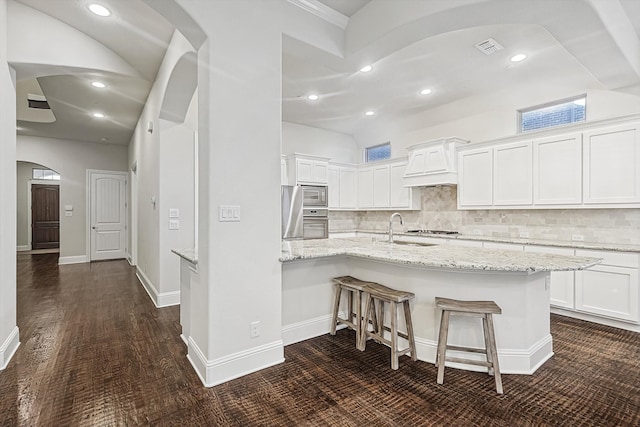 kitchen with light stone countertops, white cabinetry, appliances with stainless steel finishes, and a kitchen breakfast bar