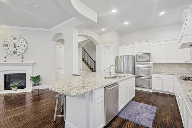 kitchen featuring sink, a kitchen island with sink, white cabinetry, stainless steel appliances, and light stone counters