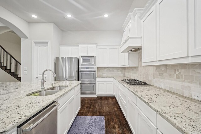 kitchen featuring sink, white cabinetry, stainless steel appliances, light stone countertops, and decorative backsplash