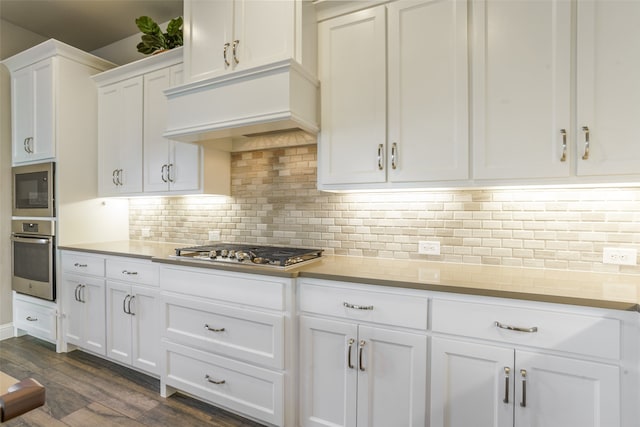 kitchen featuring white cabinetry, stainless steel appliances, tasteful backsplash, dark hardwood / wood-style flooring, and premium range hood