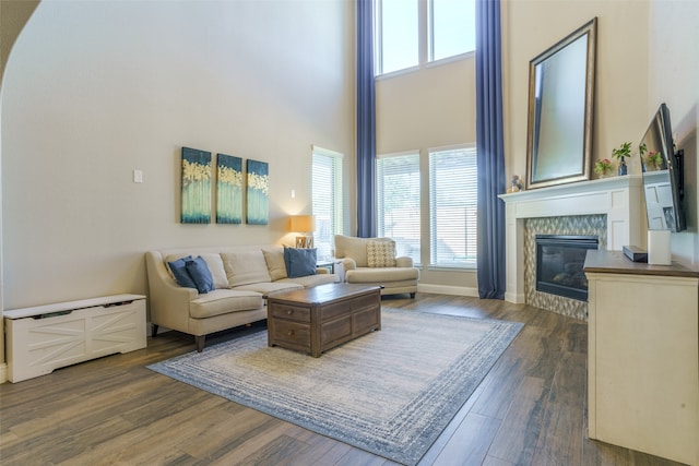 living room featuring a tile fireplace, a towering ceiling, and dark hardwood / wood-style floors