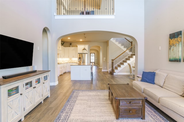 living room with light wood-type flooring and a towering ceiling