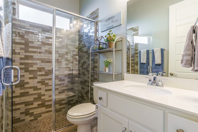 bathroom featuring vanity, a shower with door, toilet, and a wealth of natural light