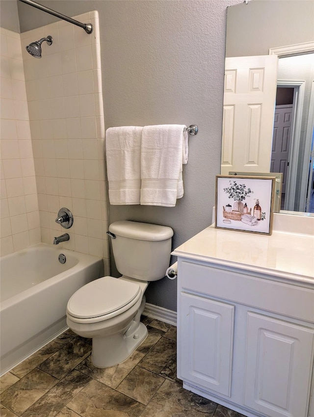 full bathroom featuring vanity, tiled shower / bath combo, and toilet