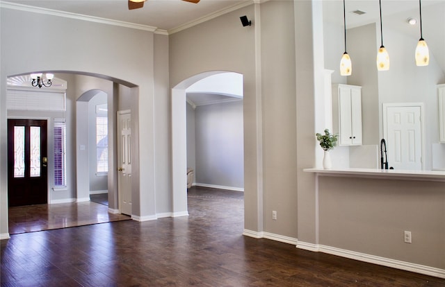 foyer with a towering ceiling, dark hardwood / wood-style floors, ceiling fan, and ornamental molding