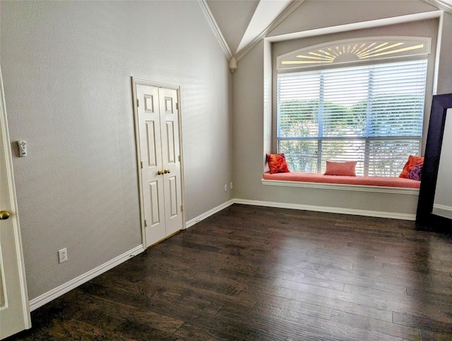 empty room featuring dark hardwood / wood-style flooring, vaulted ceiling, and ornamental molding