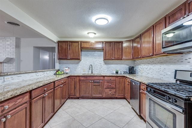 kitchen featuring decorative backsplash, stainless steel appliances, light stone countertops, and sink