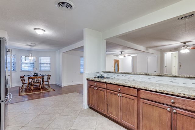 kitchen with light stone countertops, decorative backsplash, light hardwood / wood-style floors, and a textured ceiling