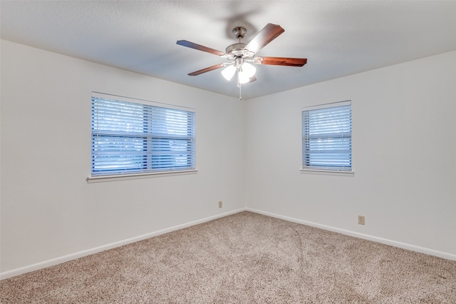 carpeted spare room featuring ceiling fan and plenty of natural light