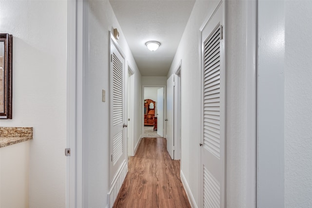 hallway featuring light hardwood / wood-style floors and a textured ceiling